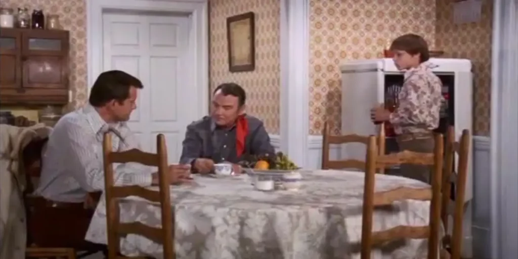 Two people sit at the dinner table and another person stands opposite them in Episode 13 of Wonder Woman (1975)