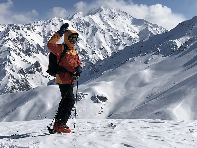 A skier waves in the middle of the snowy mountains in the film Champions of the Golden Valley, from director Ben Sturgulewski whom we interview in this article