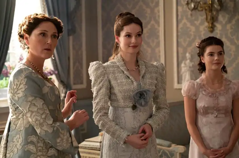 Three women stand in a room wearing nice clothes and smiling in Bridgerton, in a picture used on a Loud and Clear article about who will be the protagonist of season 4