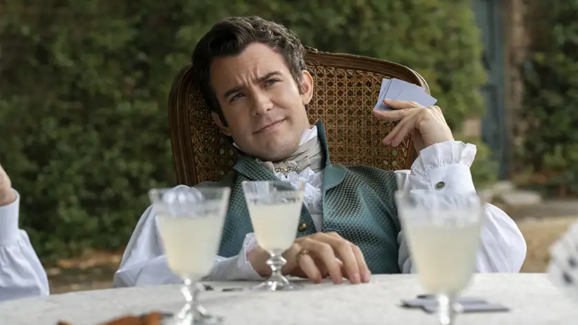 Benedict Bridgerton plays cards in Bridgerton, in a picture used on a Loud and Clear article about what to expect from season 4