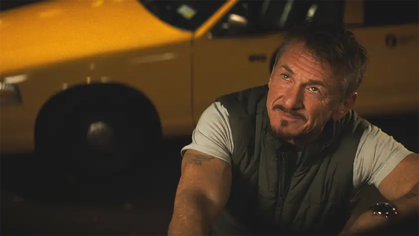 Sean Penn looks up with a yellow cab behind him in a still from Daddio