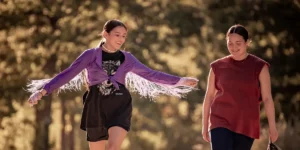 Two girls walk looking at each other and smiling in the film Fancy Dance