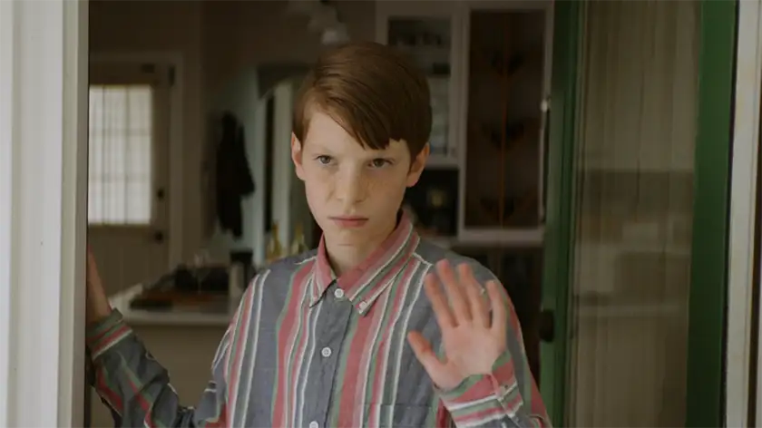 A boy wearing a striped shirt waves in the film Griffin in Summer
