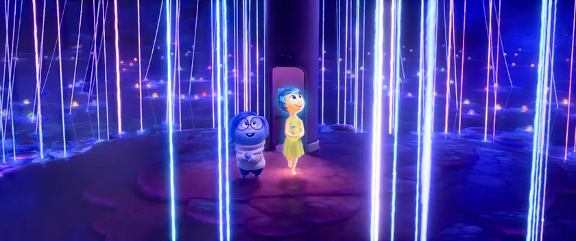Sadness and Joy walk in a place with shiny vertical strings everywhere in a still from the 2024 Disney and Pixar movie Inside Out 2