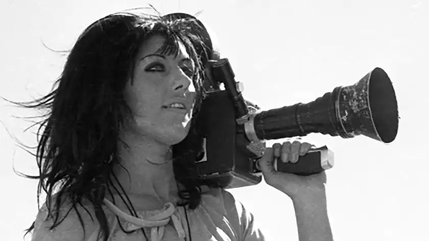 War photographer Margaret Moth holds a videocamera in a black and white still from the documentary film Never Look Away