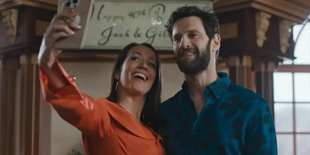 A man with a blue shirt and a woman with an orange shirt take a selfie smiling in the film Nuked