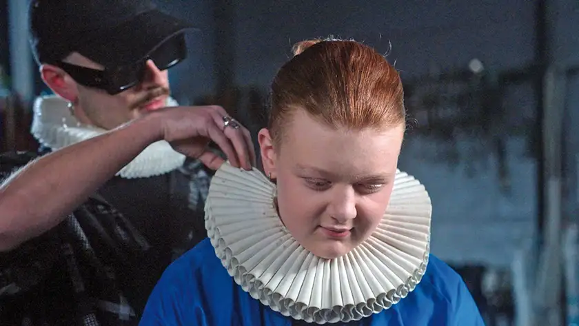 A boy puts on an Elizabethian collar on a girl in the film Orlando, My Political Biography