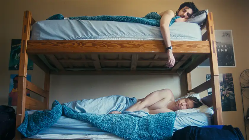 Two men are sleeping in a wooden bunk bed in the 2024 film Rent Free