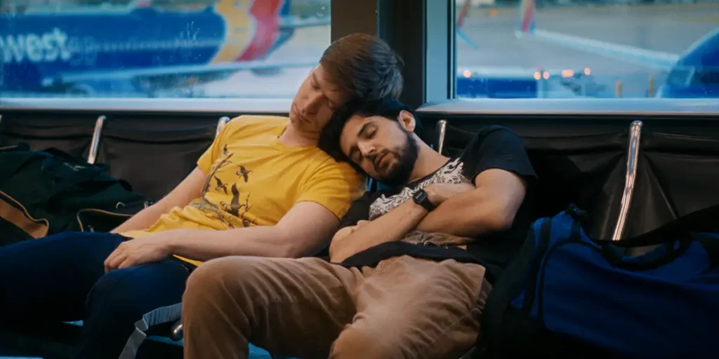 Two men are asleep in the underground, leaning on one another, in the 2024 film Rent Free