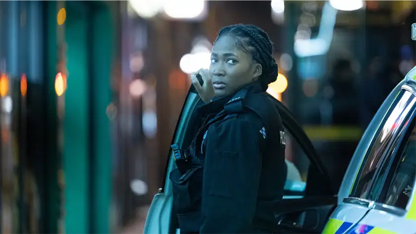 A policewoman looks back, leaning on a police car, in the BBC series The Responder Season 2