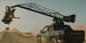 A man sitting on a stunt machine attached to a car talks to a woman inside the car in a still from the film The Fall Guy