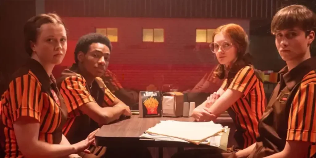 Four teenagers with striped red and black uniforms sit at a table of a fast food chain in the film The Speedway Murders