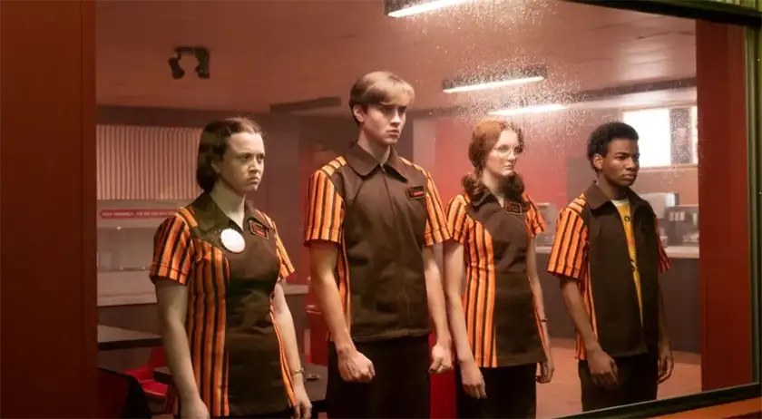 Four teenagers with striped red and black uniforms stand by a window looking sad and angry in the film The Speedway Murders