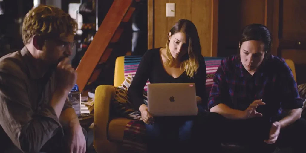 Three people sit while working on a computer in the documentary film The Grab