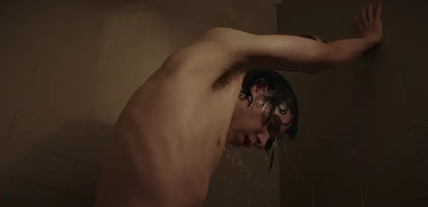 A man stands in the shower with an arm on the wall in the film This Closeness