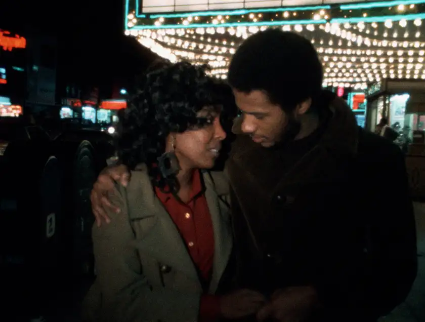 Two people hug each other while walking in the street at night in the film The Blues Under the Skin