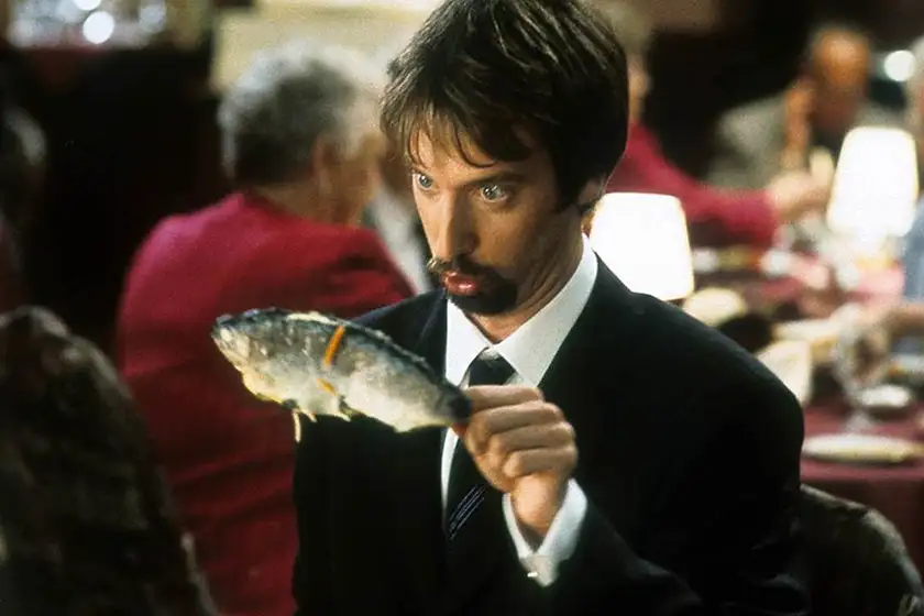 A man holds up a fish at a restaurant and makes a funny face at it in a still from the movie Freddy Got Fingered