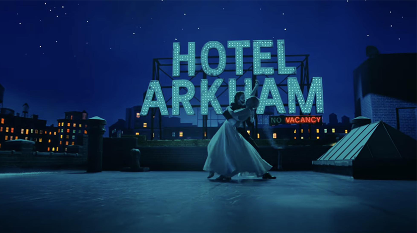 Lady Gaga and Joaquin Phoenix dance as Harley Quinn and Joker by night in front of a neon sign that reads Hotel Arkham