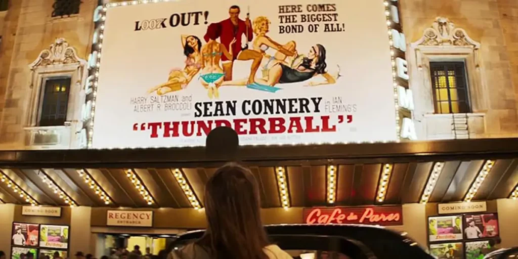 A woman stands outside a movie theater looking at a poster that reads "Sean Connery - Thunderball"