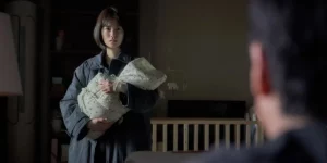 A woman holds a newborn baby looking at her husband in Jason Yu's film Sleep