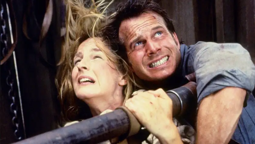 A man and a woman hold onto a rail during a tornado in the movie Twister (1996)