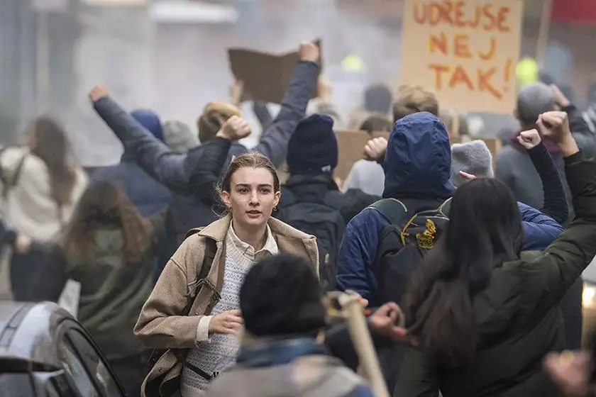 A woman runs in the middle of a protesting crowd in a still from the series Families Like Ours