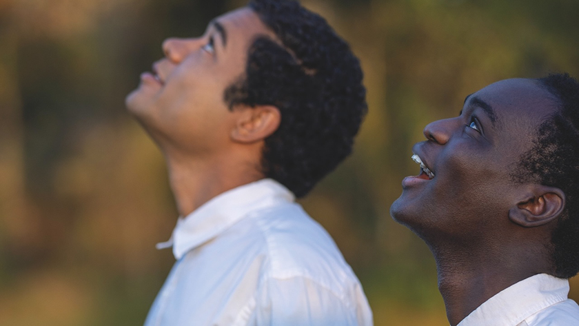 Two boys look up, smiling, in a photo taken from the side, in a still from the film Nickel Boys