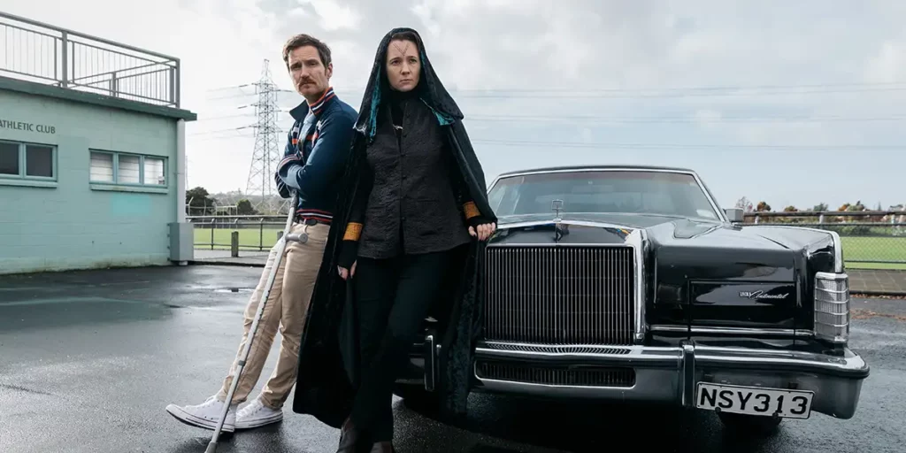 A man and a woman lean on a car in an outdoors still from the movie The Paragon