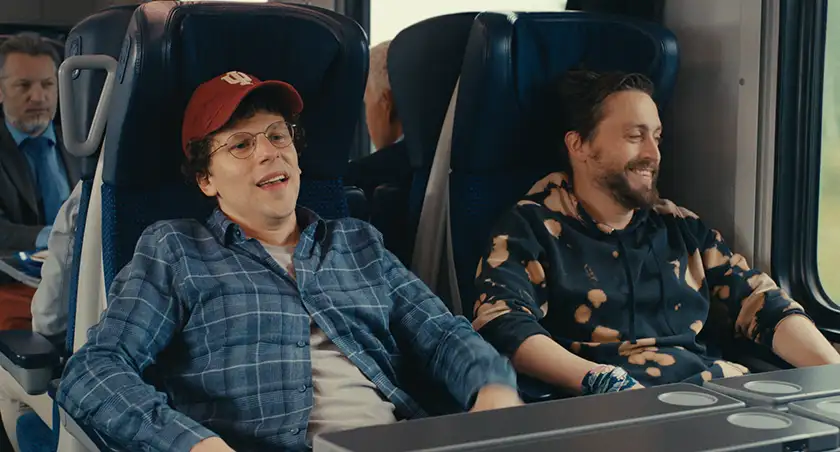 Kieran Culkin and Jesse Eisenberg sit next to each other on a train in the film A Real Pain, which cements Jesse Eisenberg’s creative focus according to Loud and Clear Reviews