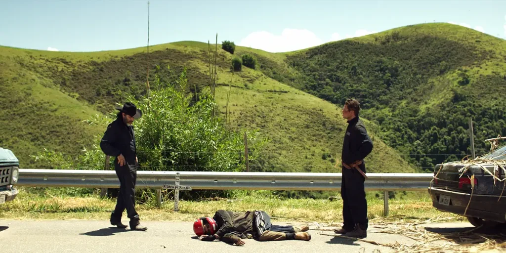 Two men stand opposite each other in front of a hill in the film Bury Your Dead