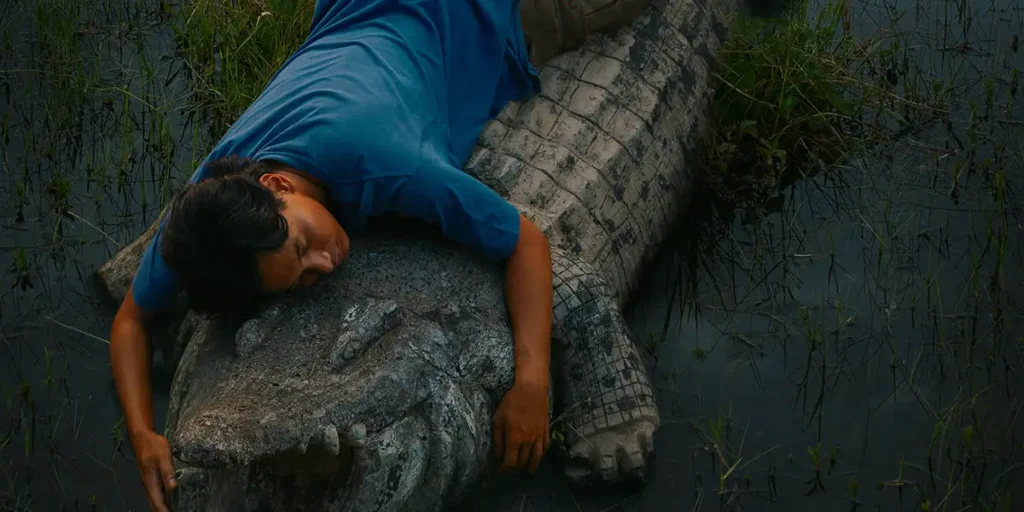 A man holds a crocodile on the ground in the film Crocodile Tears