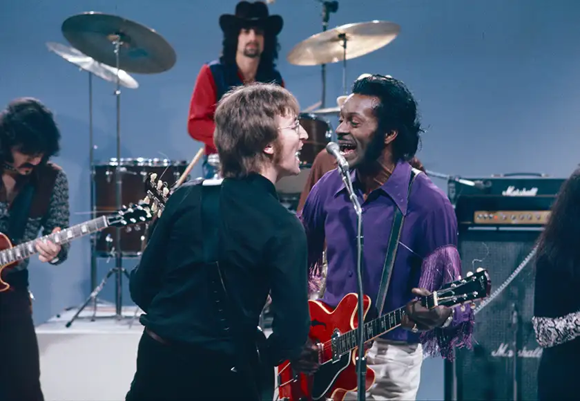 John Lennon sings with a guest in a still from the film Daytime Revolution