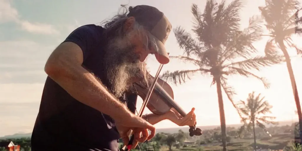 Warren Ellis plays the violin outdoors in a still from the film Ellis Park