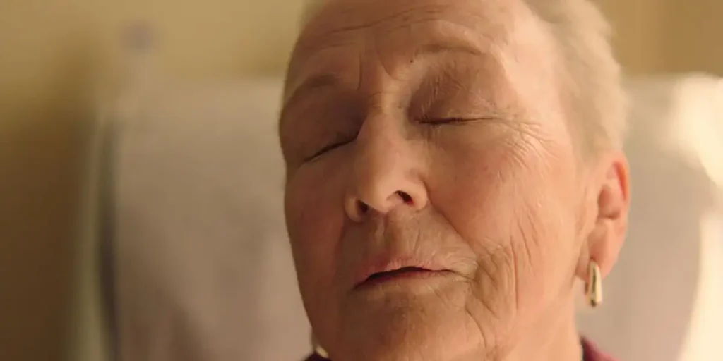 An elderly lady closes her eyes in a still from the film Familiar Touch