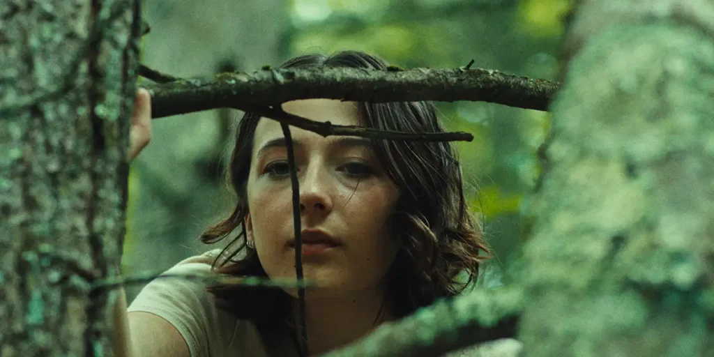 A woman looks at a tree in the woods in a still from the film Good One