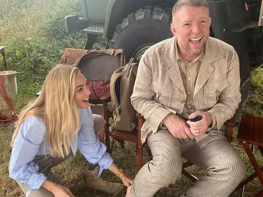 Two people laugh in a behind the scene still from the Guy Ritchie movie In The Grey, featured in an article with everything we know about the movie