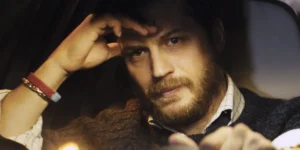 Tom Hardy drives a car as Ivan Locke, deep in thought, in a still from the film Locke, whose complex morality is analyzed in Loud and Clear's article