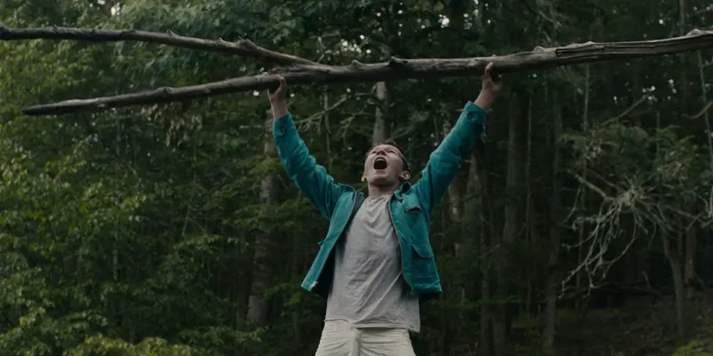 A child holds a tree branch in triumph in a still from the film Lost on a Mountain in Maine