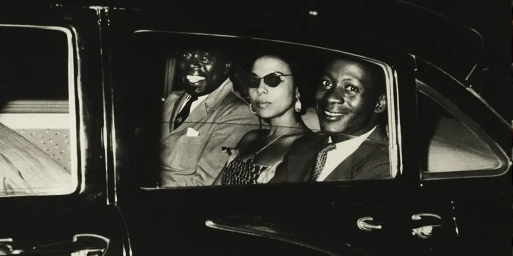 Three people are in a car in a black and white still from the film Soundtrack to a Coup d'État