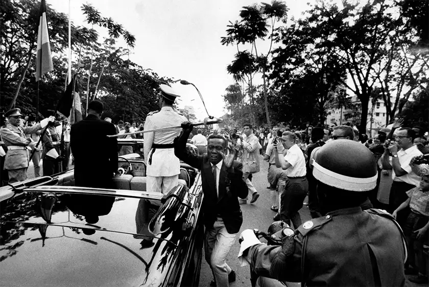 A man runs in a black and white still from the film Soundtrack to a Coup d'État