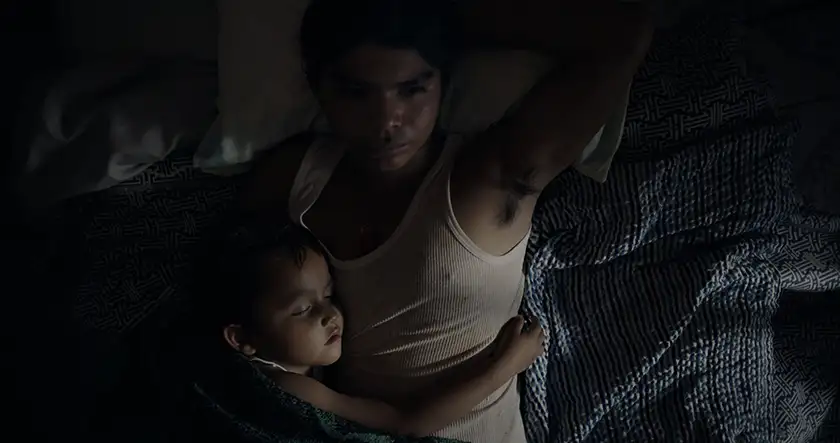 A man and his son are in bed, sleeping, in a still from the film Sujo