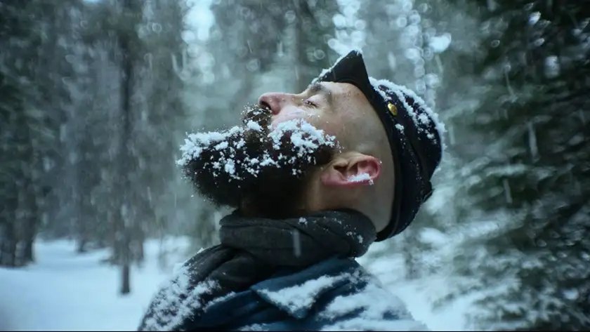 A soldier has his head towards the sky with eyes closed as snow falls on his face and all around him in a still from the Roberto Minervini film The Damned