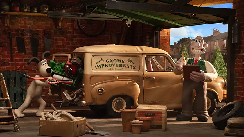 An animated man and dog are assembling a van with the writing "Gnome Improvements" on it in a still from the 2024 film Wallace & Gromit: Vengeance Most Fowl