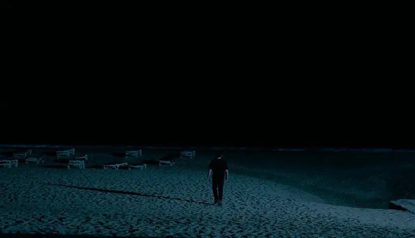 Calum walks alone on the beach at night in a scene from Charlotte Wells's Aftersun, which is explained in this article where we decode Sophie's memories