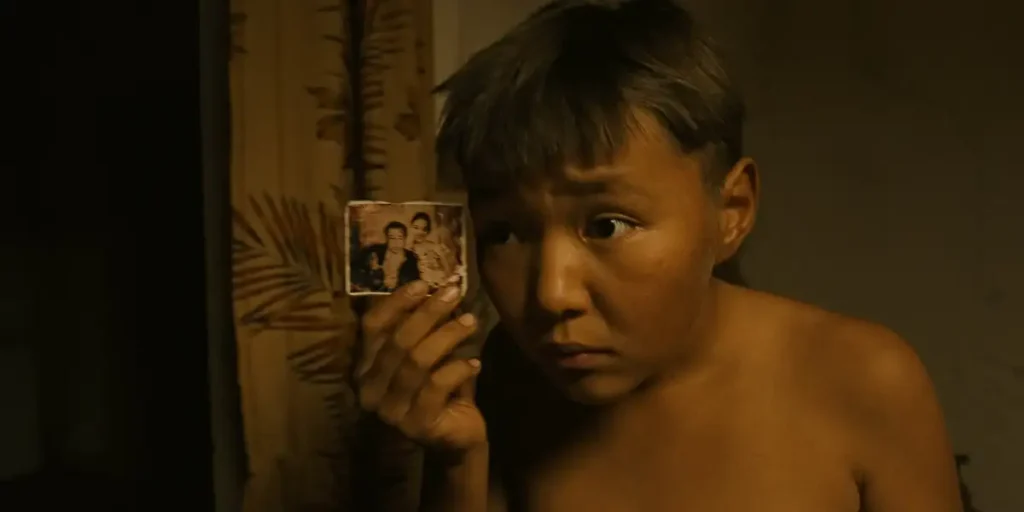 A boy holds up a photograph in the film Bauryna Salu