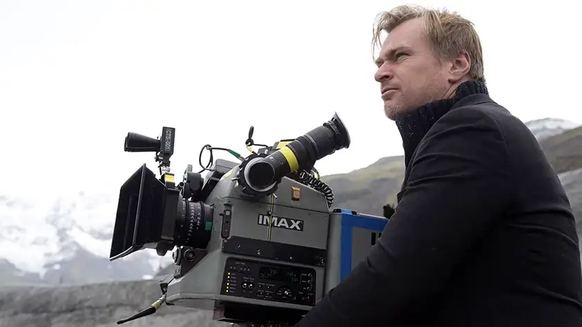 Christopher Nolan next to his IMAX camera on the set of Interstellar, in a picture featured in an article with everything We Know About the New Nolan Movie