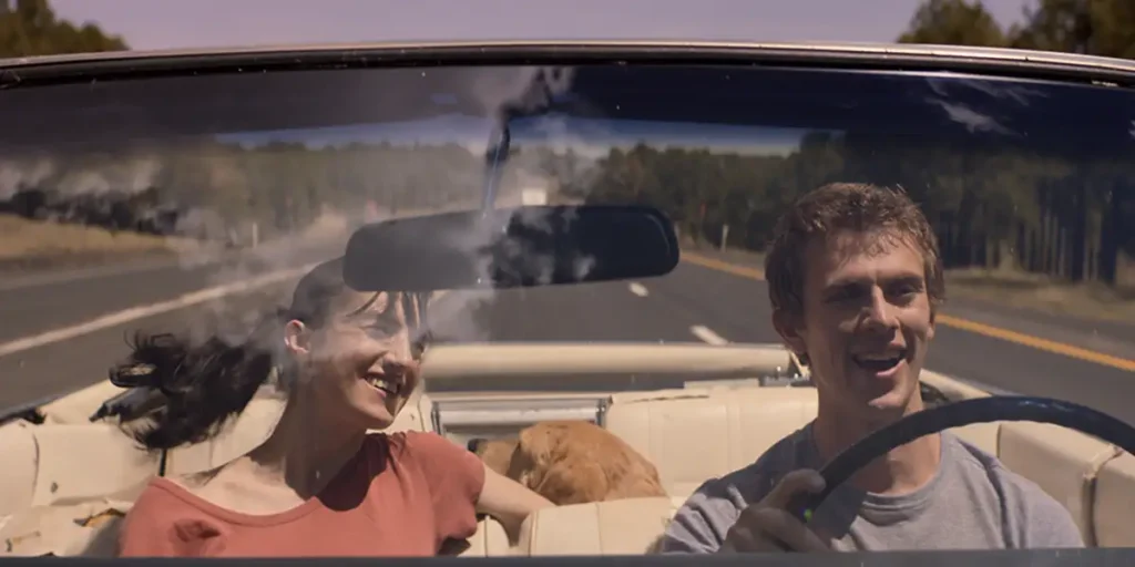 A boy and a girl in a car are on a road trip in a still from the movie What We Find on the Road