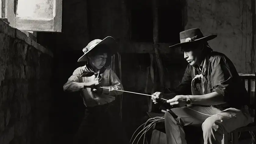 A young cowboy pulls a rope from another who is sitting in a still from the film Gaucho Gaucho