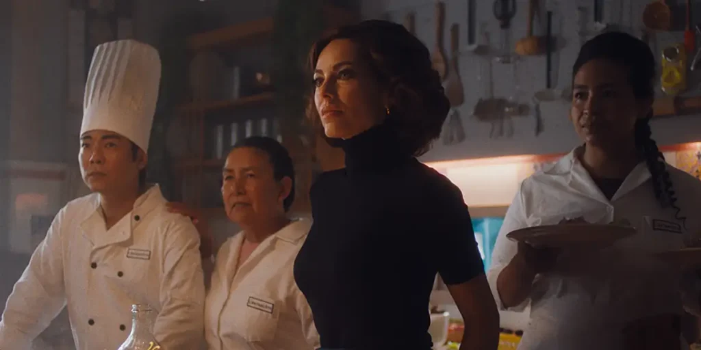 Two women and a chef stand in a restaurant looking in front of them in a still from the film Mistura