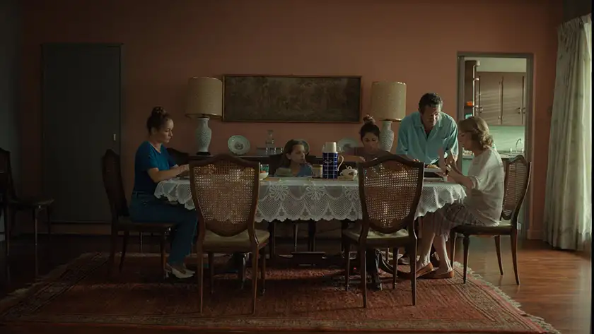 A family has lunch sitting at a table in a still from the film Queens (Reinas)